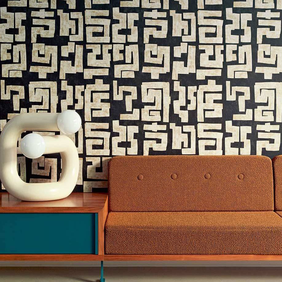 Moderne interieursetting met Elitis-behang uit de Voile de Papier-collectie, een oranje retrobank en een sculpturale tafellamp.