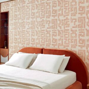 Slaapkamer met Elitis-behang Message TP 331 uit de Voile de papier collectie in aardetinten achter een bed met ronde, oranje gestoffeerde achterwand.