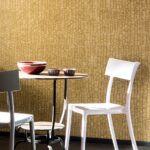 Tafel met moderne stoelen en aardewerk voor een Elitis Natural Mood behang in warme, geweven textuur.