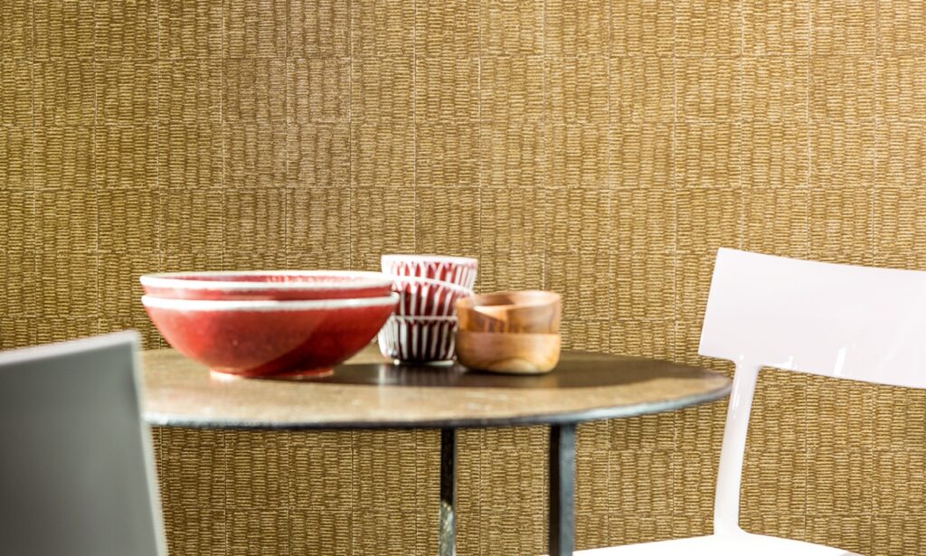 Ronde tafel met keramische en houten kommen voor een Elitis-behang met natuurlijke textuur.