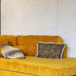 Gele fluwelen bank met sierkussens tegen een muur met Elitis-behang in de stijl Natural Mood.