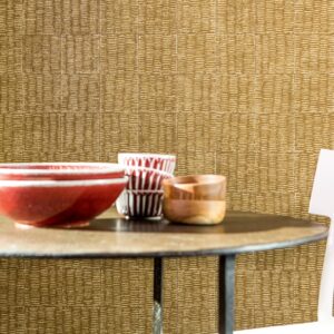 Ronde tafel met keramische en houten kommen voor een Elitis-behang met natuurlijke textuur.