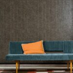 Groenblauwe bank met oranje kussen staat voor een muur met Elitis-behang uit de Natural Mood-collectie (VP 915 19).