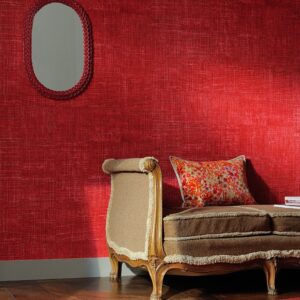 Klassiek bankje met kussen staat voor een rode wand met Elitis-behang Raffia.