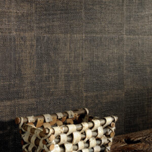 Donker Elitis-behang Raffia VP 601 80 met grove textuur, gecombineerd met een decoratief houten mandje op de voorgrond.