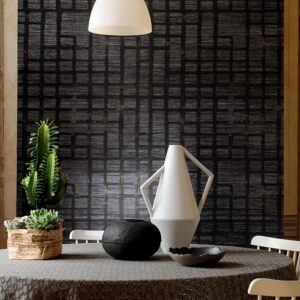 Moderne eetkamer met Elitis-behang Talamone Parla con me VP 853 04 in donker geometrisch patroon en decoratieve accessoires op een ronde tafel.