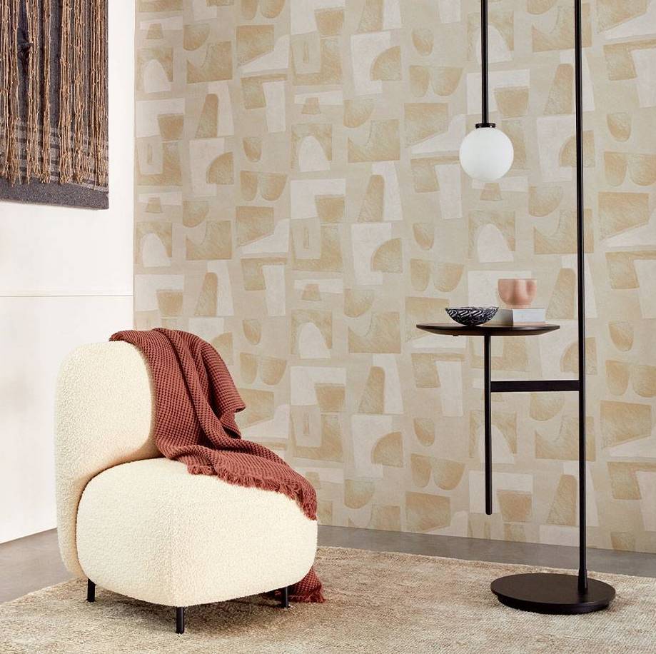 Moderne zithoek met Elitis Tutto TP 333 behang uit de Voile de papier collectie, een crèmekleurige fauteuil, en een minimalistische zwarte bijzettafel.