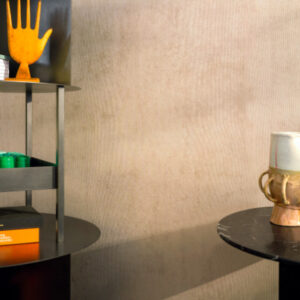 Moderne interieurhoek met Elitis Alcove behang en decoratieve objecten op zwarte tafels.