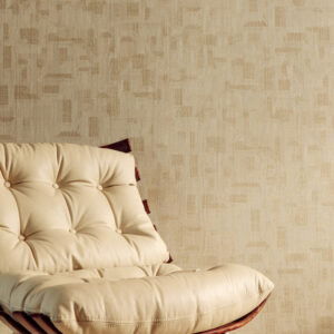 Beige Elitis-behang Bois Sculpte Ramille VP 938 20 met abstract reliëfpatroon achter een crèmekleurige, gecapitonneerde designstoel.