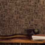 Donkerbruin Elitis-behang Bois Sculpté Ramille met geometrisch houtstructuurpatroon, gecombineerd met een golvende houten plank en decoratieve objecten.