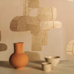 Aardekleurige Elitis Hanji Takara RM 1062 04 behang met abstract patroon, gecombineerd met keramieken vaas en kommetjes.