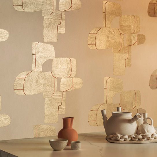 Sfeervol interieur met Elitis Hanji Takara RM 1062 04 behang in goudtinten en keramisch servies op een marmeren tafel.