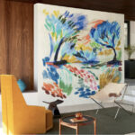 Moderne zithoek met kleurrijk Elitis-behang "La Caravane au Pied du Ventoux" als kunstzinnige eyecatcher op de muur.