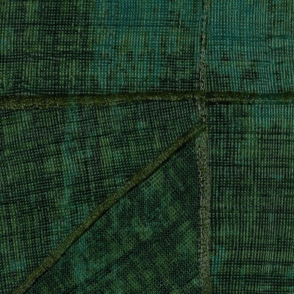 Donkergroen Elitis-behang uit de La Caravane Chogak collectie met een patchwork van geweven textuurvlakken.