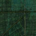Donkergroen Elitis-behang uit de La Caravane Chogak collectie met een patchwork van geweven textuurvlakken.