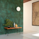Moderne interieurhoek met Elitis behang La Caravane Chogak VP 943 in groen, houten bankje en decoratieve objecten.