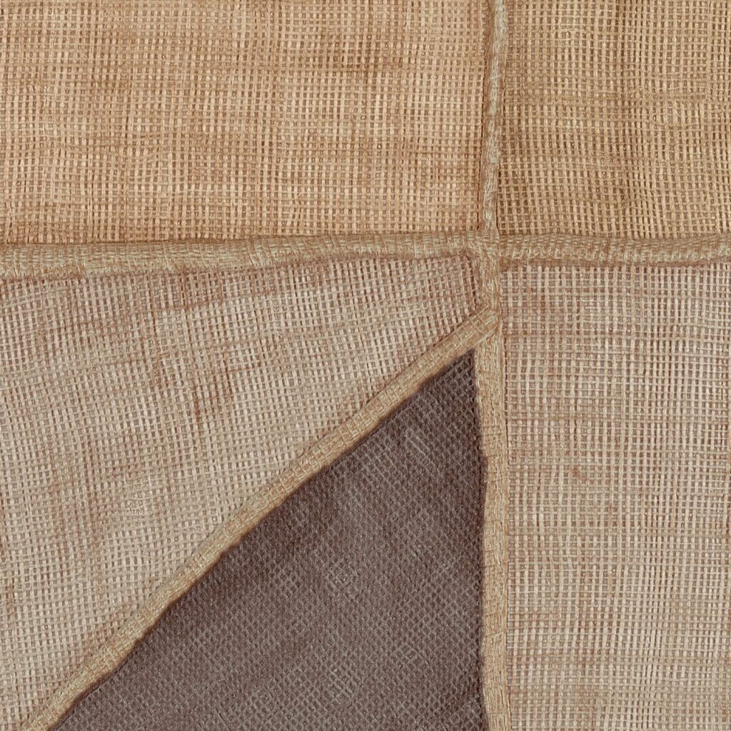 Close-up van Elitis behang uit de La Caravane Kungbo VP 944 05 collectie met een geweven, patchwork-achtige textuur in aardetinten.