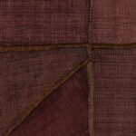 Detailopname van het Elitis-behang La Caravane Kungbo VP 944 09 met een patchworkstructuur in warme rood- en bruintinten.