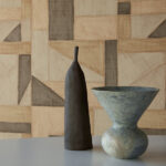 Twee keramische vazen voor een Elitis La Caravane Kungbo VP 944 behang met geometrisch patroon in aardetinten.