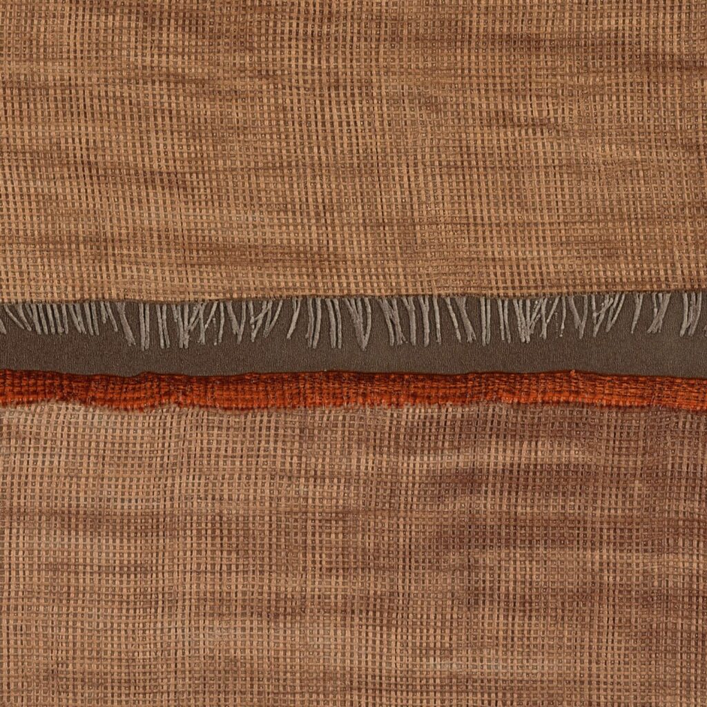 Detail van Elitis behang La Caravane Moshi Moshi VP 942 05 met een geweven textuur in aardetinten en decoratieve franjes.