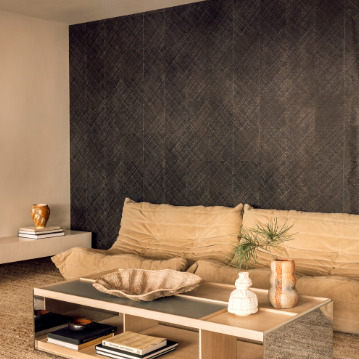 Moderne woonkamer met Elitis Buri behang in donkere tinten, een beige loungebank en een houten salontafel met decoratieve objecten.