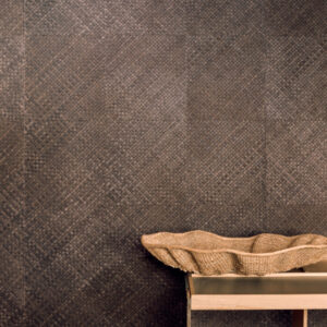 Donkerbruin Elitis-behang van plantaardig materiaal met geweven textuur, met een decoratieve mand op een houten tafel.
