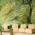 Moderne zithoek met lichtbeige fauteuils en een groen Elitis Manihi behang met groot palmbladmotief.