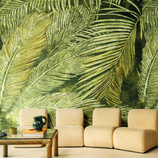 Moderne zithoek met lichtbeige fauteuils en een groen Elitis Manihi behang met groot palmbladmotief.