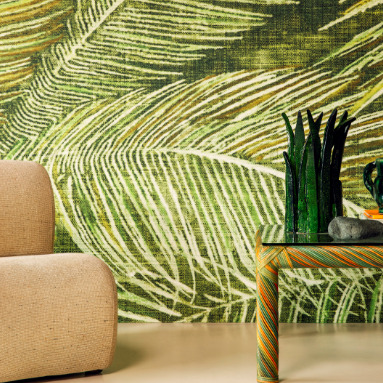 Zithoek met Elitis Manihi behang met groen bladmotief, beige fauteuil en decoratieve accessoires op een glazen tafel.