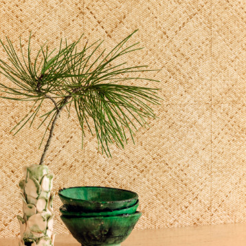 Groene keramieken kommen en een vaasje met dennentak voor Elitis behang Matieres Végétales VP 984 02.