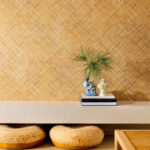 Interieur met Elitis behang Matières Végétales VP 984 04, rotan kussens en decoratieve objecten op een lichte plank.