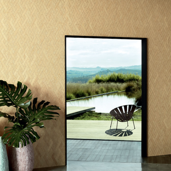 Moderne interieursetting met Elitis Merida behang en uitzicht op een terras met designstoel aan het water.