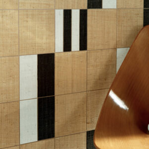 Detail van Elitis behang Merida Wall Partitura RM 1020 80 met geometrisch patroon in beige, zwart en wit, naast een houten stoel.