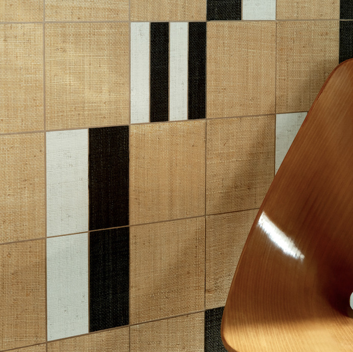 Detail van Elitis behang Merida Wall Partitura RM 1020 80 met geometrisch patroon in beige, zwart en wit, naast een houten stoel.