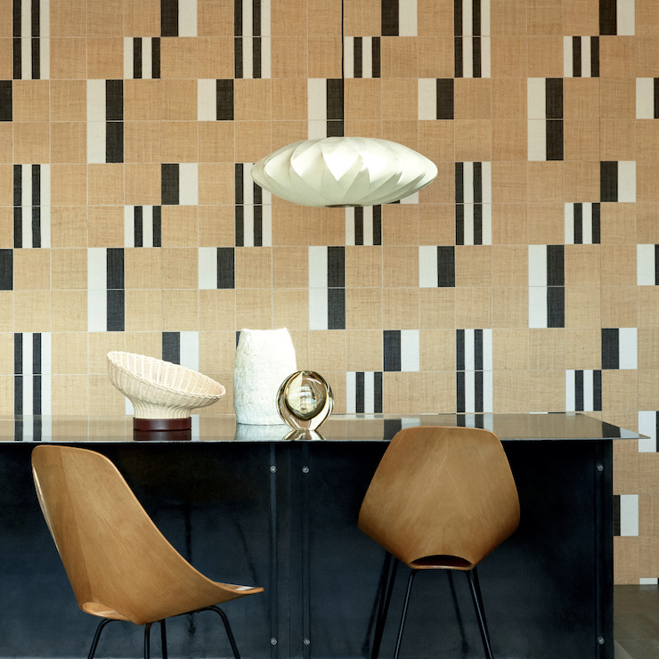 Moderne interieursetting met Elitis Merida Partitura RM 1020 80 behang in geometrisch patroon achter een zwarte tafel en houten stoelen.
