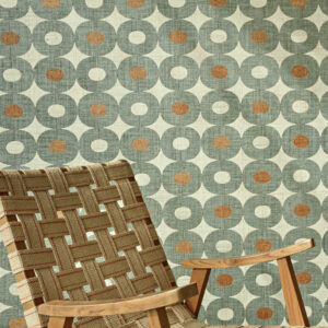 Groen Elitis Merida behang met retro geometrisch patroon en houten stoel met geweven zitting.