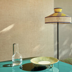 Moderne interieursetting met Elitis Merida behang, een glazen karaf, een decoratief bord en een design vloerlamp.
