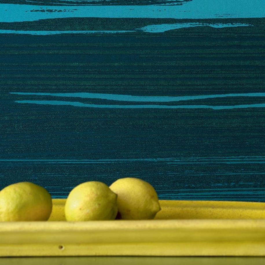 Drie citroenen op een gele schaal voor een donkerblauw Elitis-behang met abstract patroon uit de Mouvements Esprit Libre collectie.