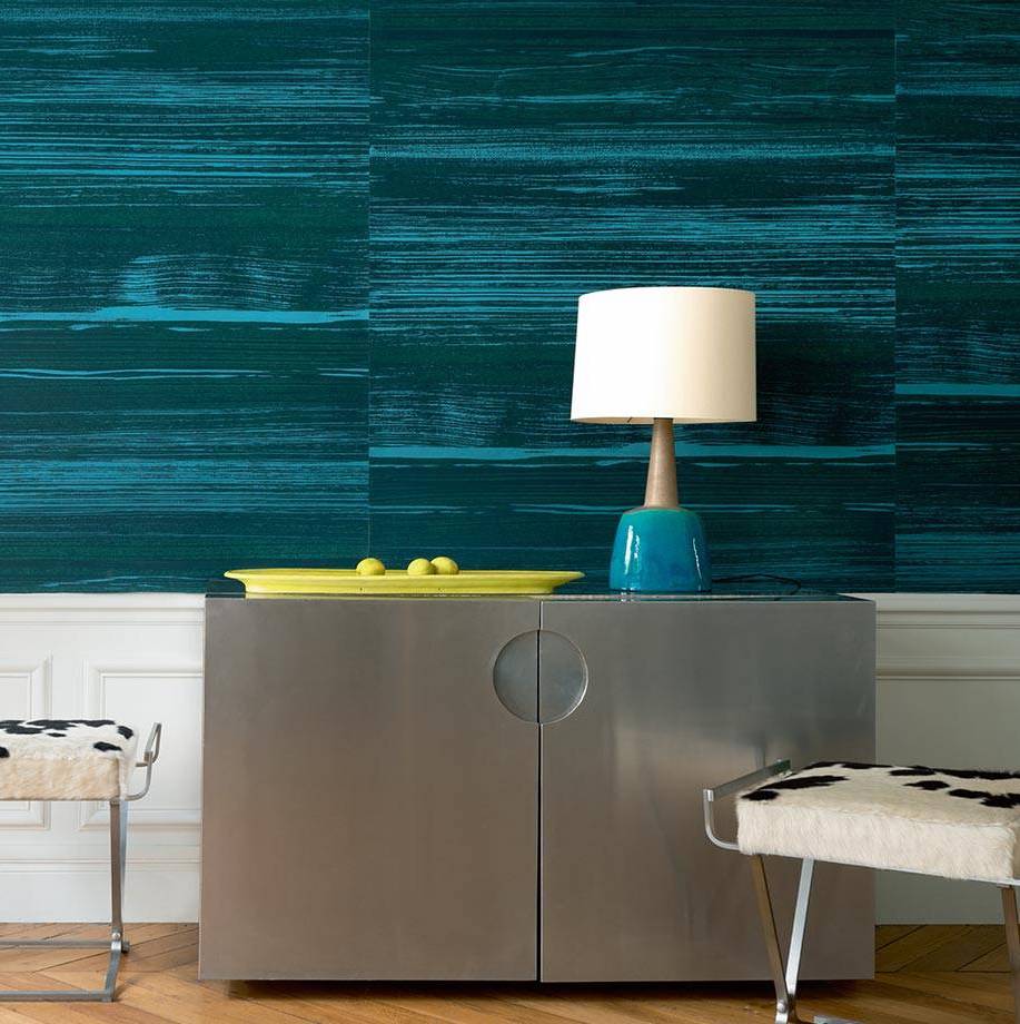 Modern interieur met Elitis-behang Mouvements Esprit Libre in blauwgroene tinten, metalen kast, designlamp en decoratieve krukjes.