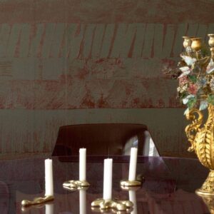 Close-up van een interieur met Elitis-behang Mouvements Impulsion RM 1022-65, een glazen tafel met moderne kandelaars en een decoratieve gouden kandelaar.