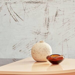 Sfeervol interieur met Elitis behang Tableau Rose TP 335 01 uit de Voile de Papier collectie, met een ronde vaas en glazen schaal op een lichtgekleurd tafelblad.