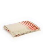 Opgevouwen Elitis Betty Amarante plaid in crème met rode, roze en oranje strepen en franjes.