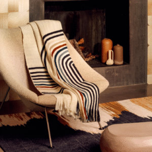 Designstoel met een Elitis Betty PL 308 86 02 Nuit plaid gedrapeerd in een warme, moderne interieursetting.