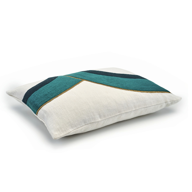 Sierkussen Elitis Bridge CO 216 46 02 met een wit linnen ondergrond en geometrisch patroon in turquoise, donkerblauw en goud.