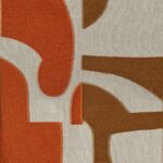 Close-up van de Elitis Cancun LZ 893 39 stof met retro-geïnspireerd abstract patroon in oranje en bruin op een beige ondergrond.
