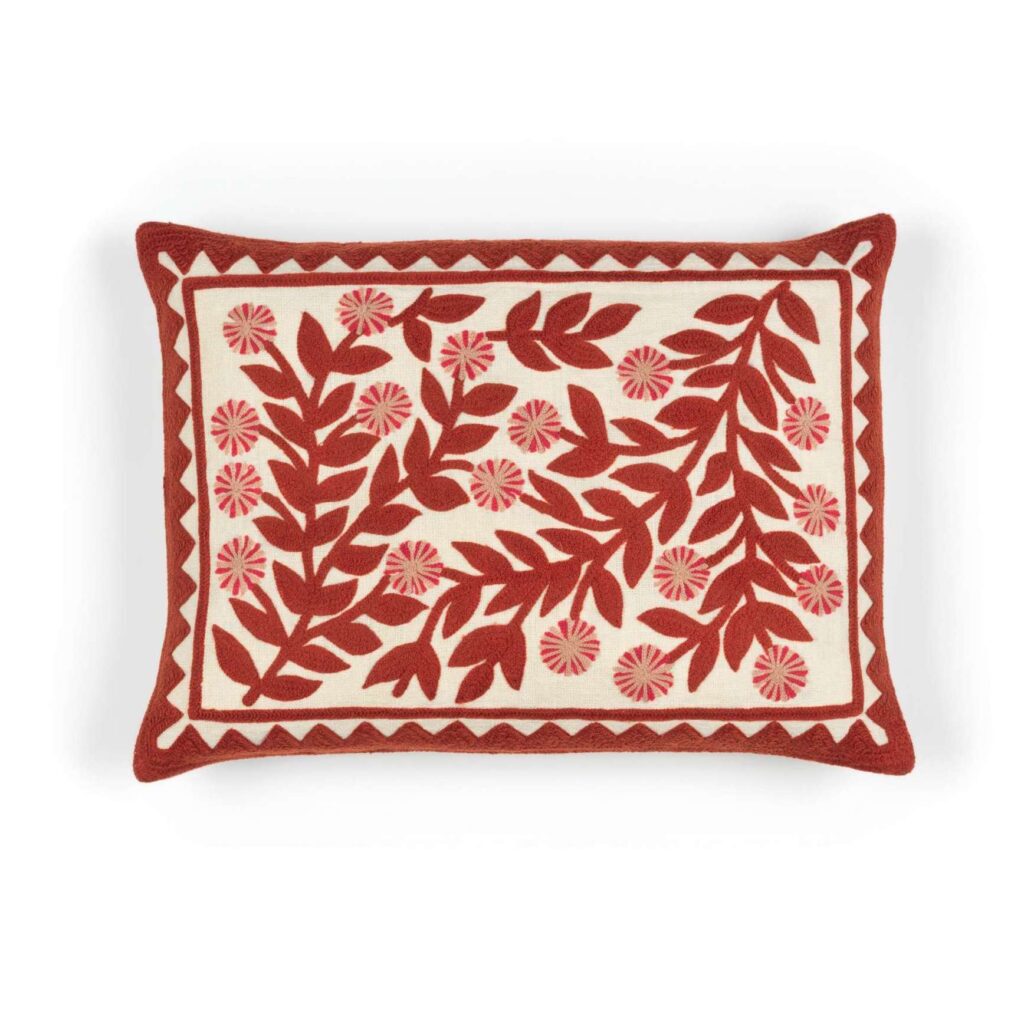 Rechthoekig Elitis Canopee kussen met rood botanisch borduursel op een crème achtergrond.