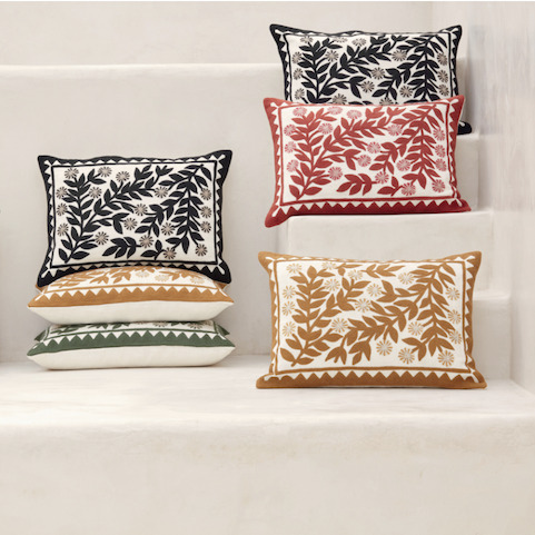 Sierkussens uit de Elitis Canopée collectie met geborduurde bladvormen in verschillende kleuren op een witte achtergrond, gestyled op witte traptreden.