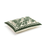 Zijaanzicht van het Elitis Canopee kussen met groen botanisch borduurwerk op een crèmekleurige achtergrond.
