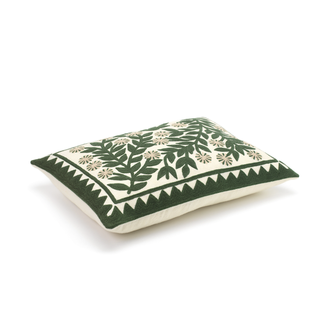 Zijaanzicht van het Elitis Canopee kussen met groen botanisch borduurwerk op een crèmekleurige achtergrond.