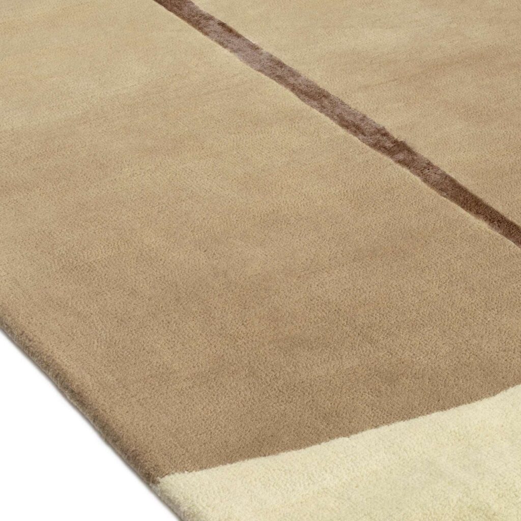 Detail van het Elitis Celeste TA 133 17 02 vloerkleed met beige oppervlak, donkere streep en lichtgekleurde rand.